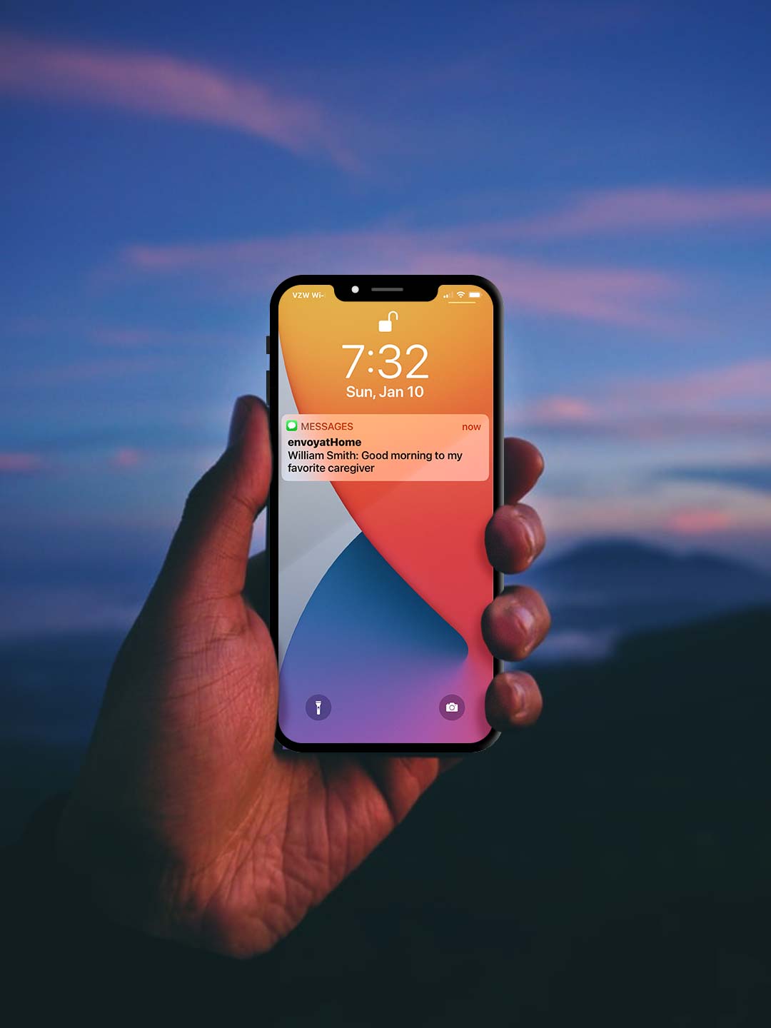 Hand holding a cell phone showing a text alert from envoyatHome