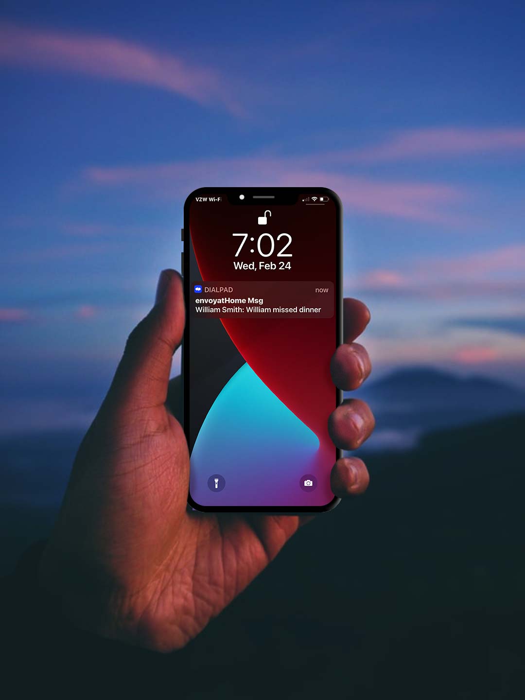 Hand holding a cell phone showing a text alert from envoyatHome