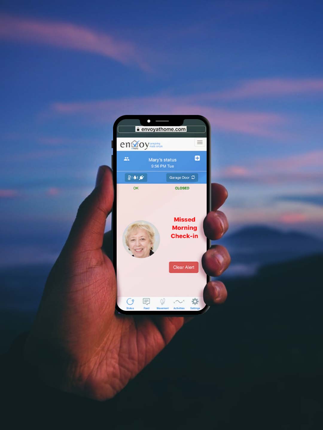 Hand holding a cell phone showing an update that a morning check-in was missed on the envoyatHome app